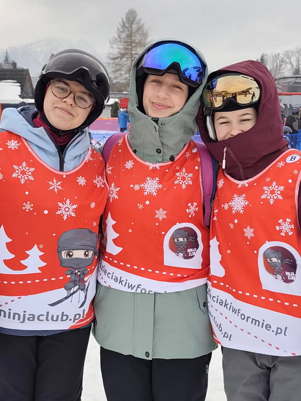 Trzy uczestniczki obozu w klubowych plastronach na stoku